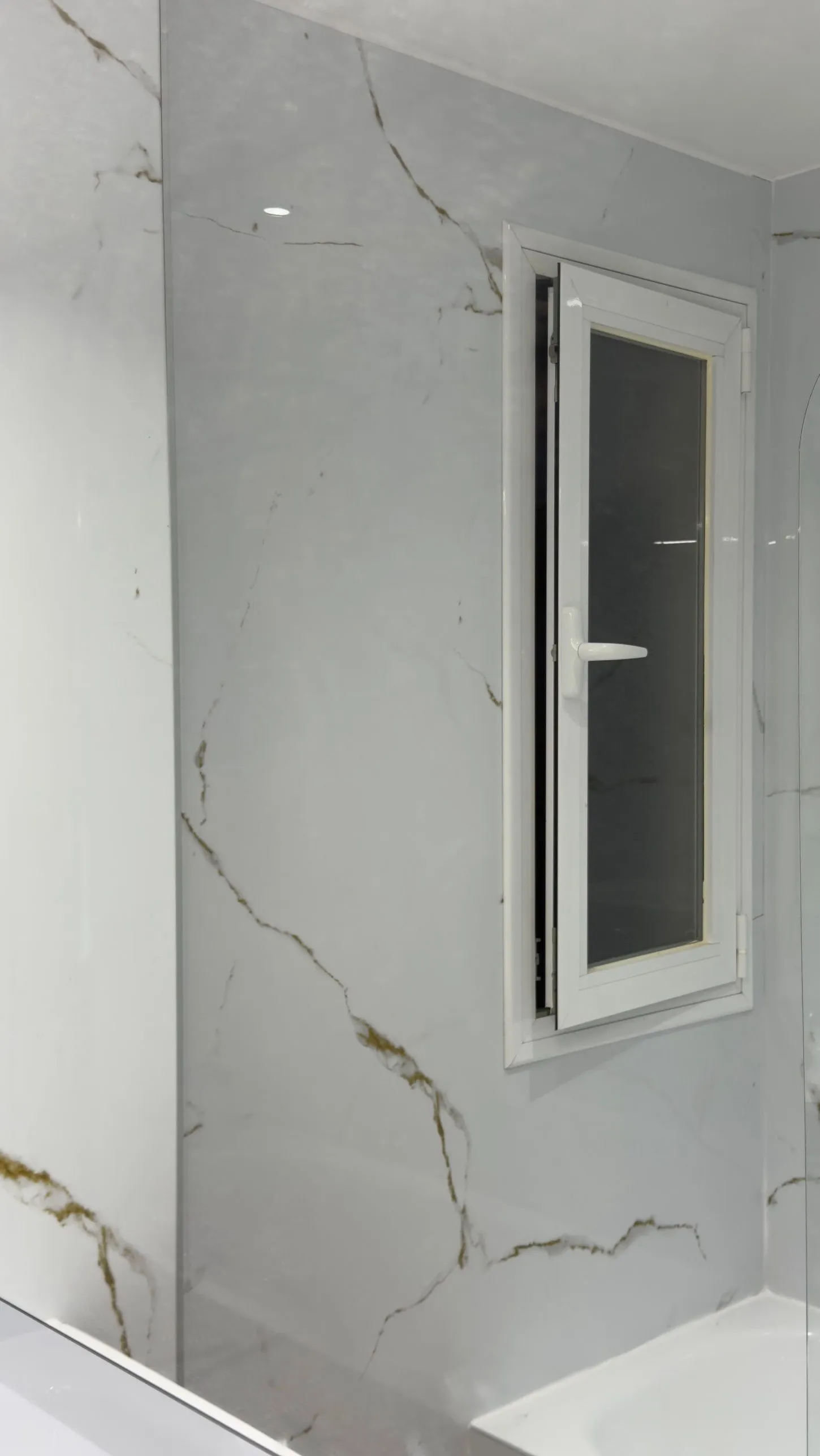 Pared del baño revestida con Kobert In efecto mármol alrededor de la ventana