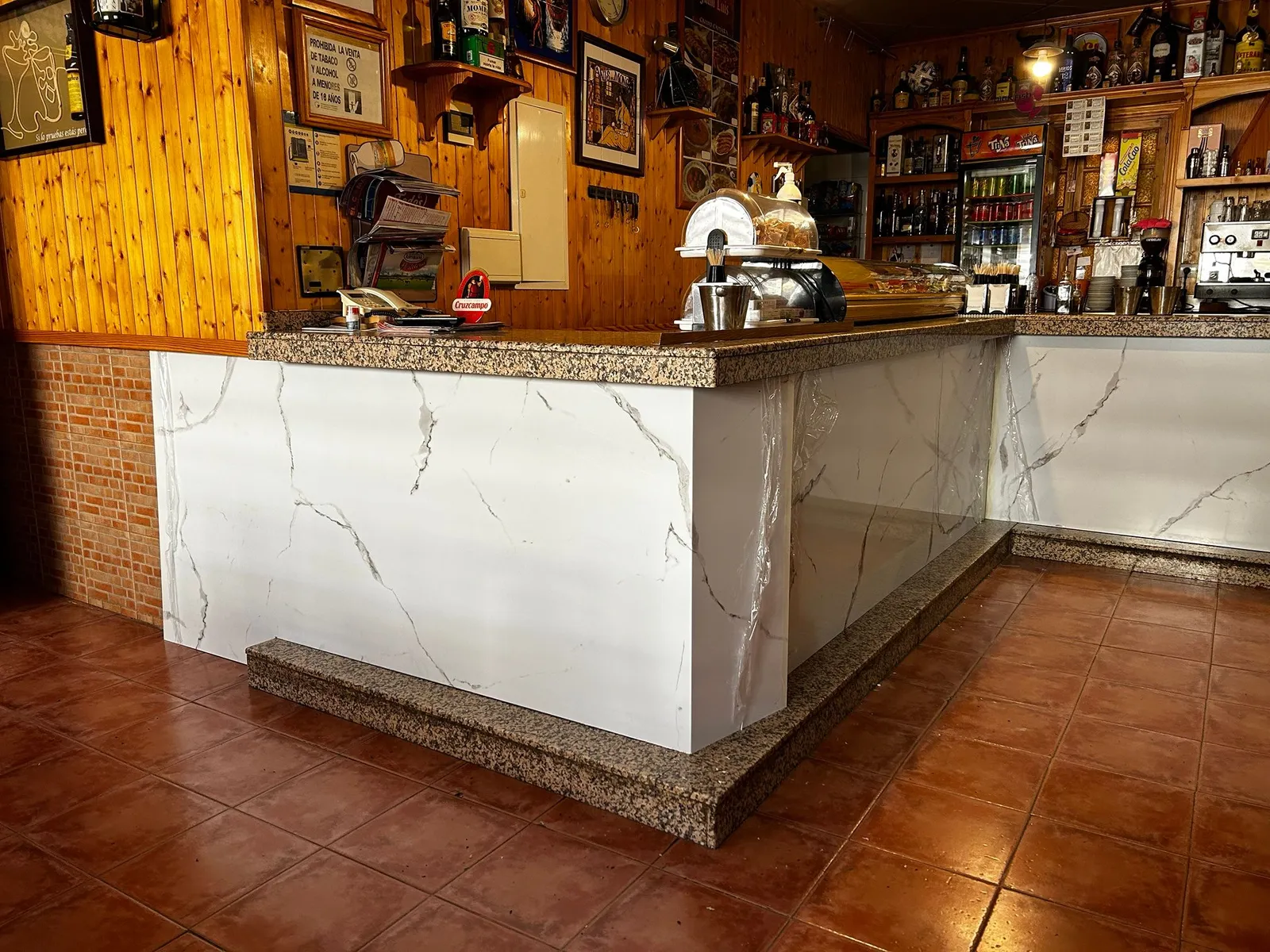 Frente de barra de bar revestido con Kobert In efecto mármol bajo encimera de granito