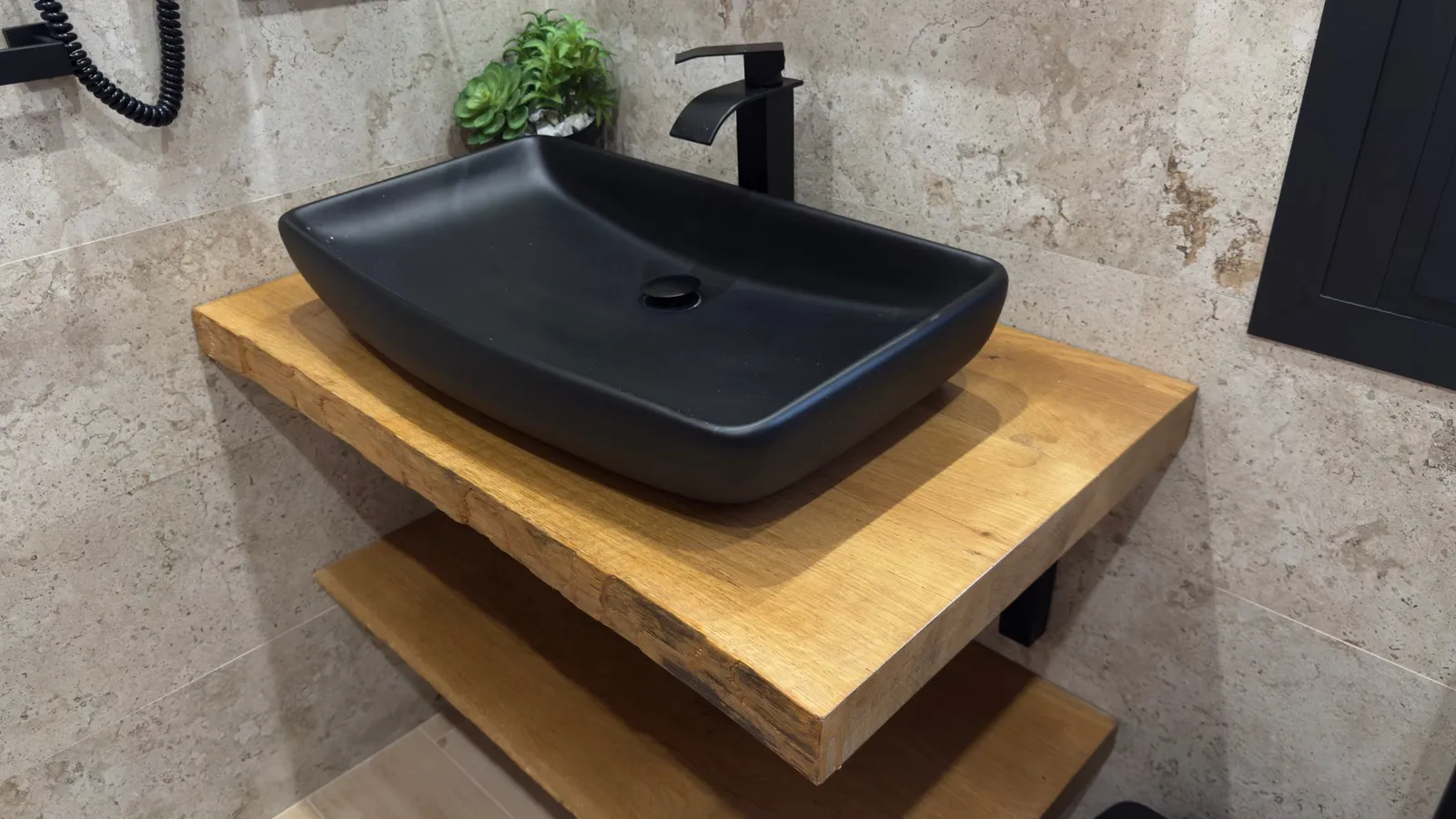 Encimera de madera maciza con canto natural y lavabo negro sobre encimera
